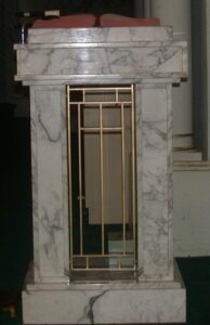 A marble fireplace with gold bars on the side.