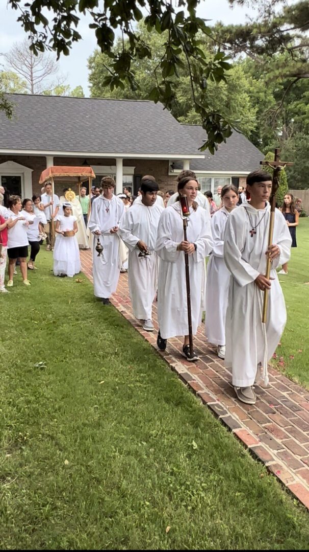 A group of people in white robes walking down the sidewalk.