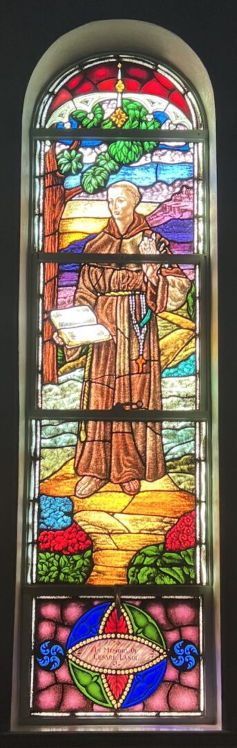 A stained glass window of st. Francis holding a book