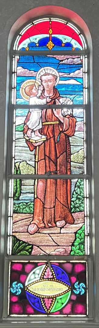 A stained glass window of jesus holding the cross.