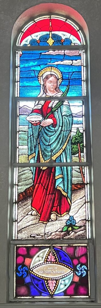 A stained glass window of jesus holding the cup.