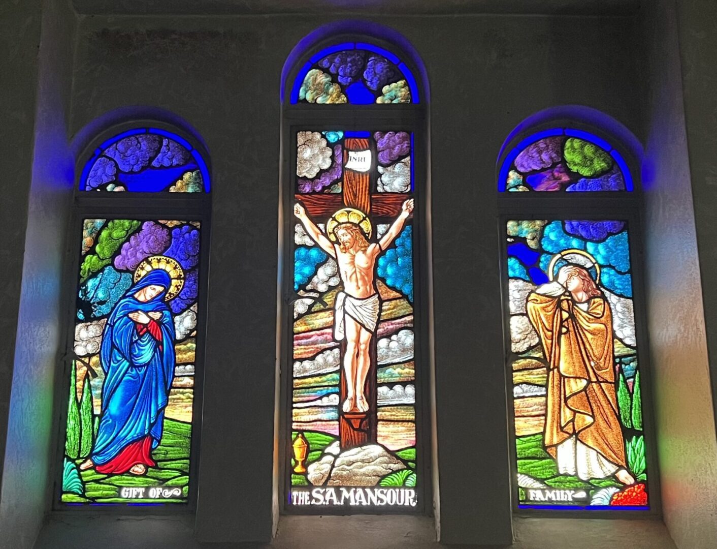 A stained glass window depicting jesus, mary and st. John